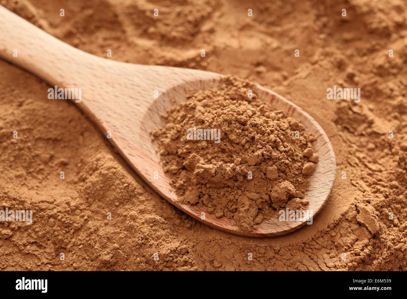 Cocoa powder in a wooden spoon on cocoa powder background. Closeup. Stock Photo