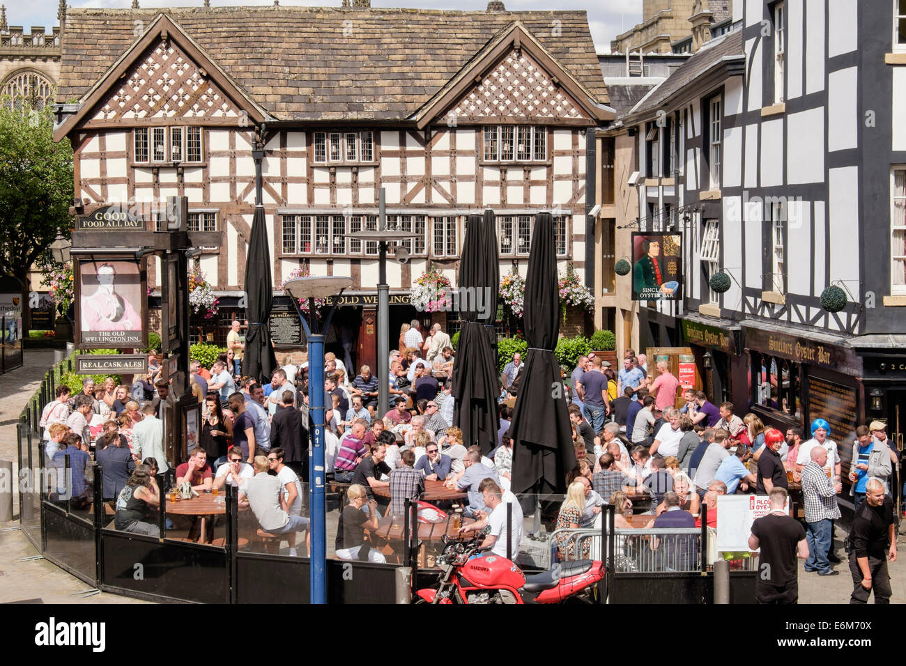 Sinclair's Oyster Bar and 16thc timbered The Old Wellington Inn with crowds of people in busy beer garden outside. Manchester UK Stock Photo