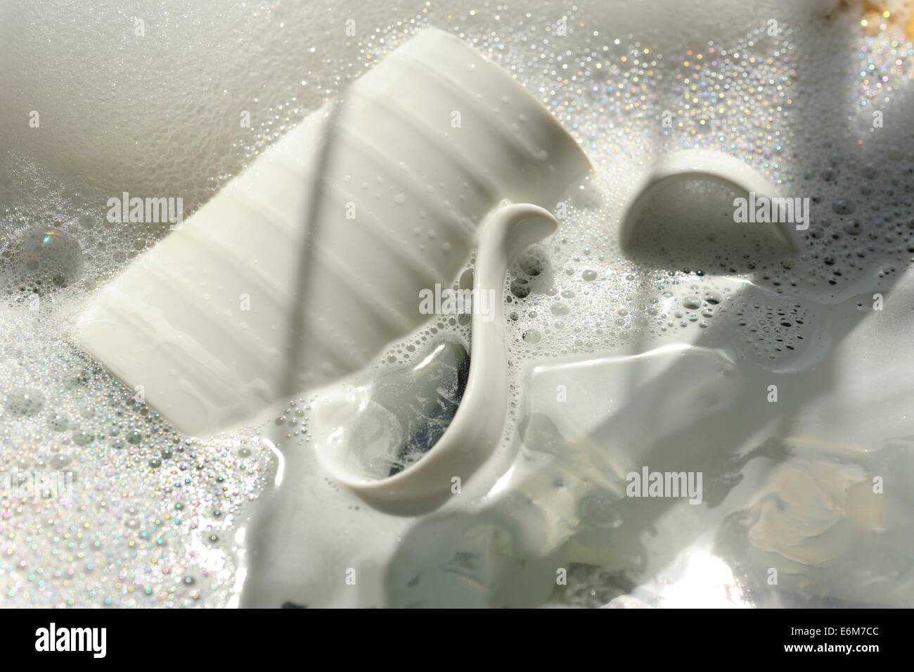 A white ceramic mug soaking in soap suds Stock Photo