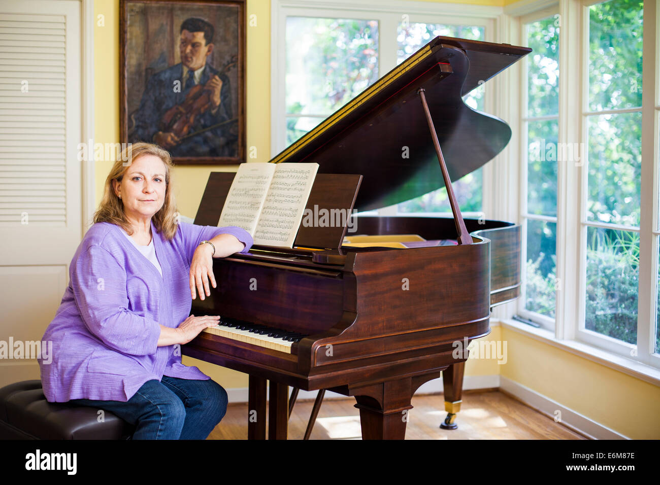 Woman sitting next to piano Stock Photo