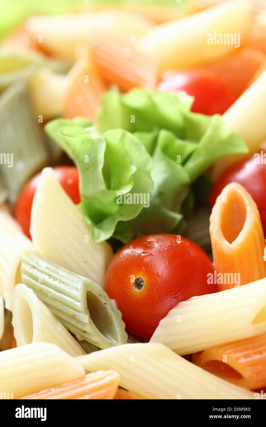 Rigatoni (penne rigate pasta) with tomatoes and lettuce. Closeup. Stock Photo