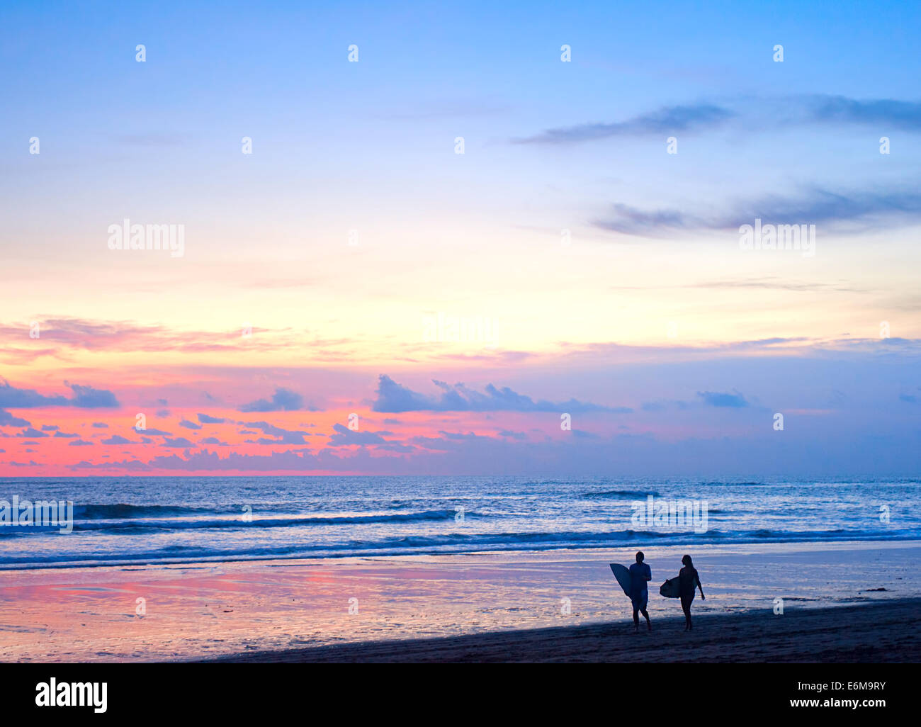 Couple of surfers walking on the beach on Bali island, Indonesia Stock Photo