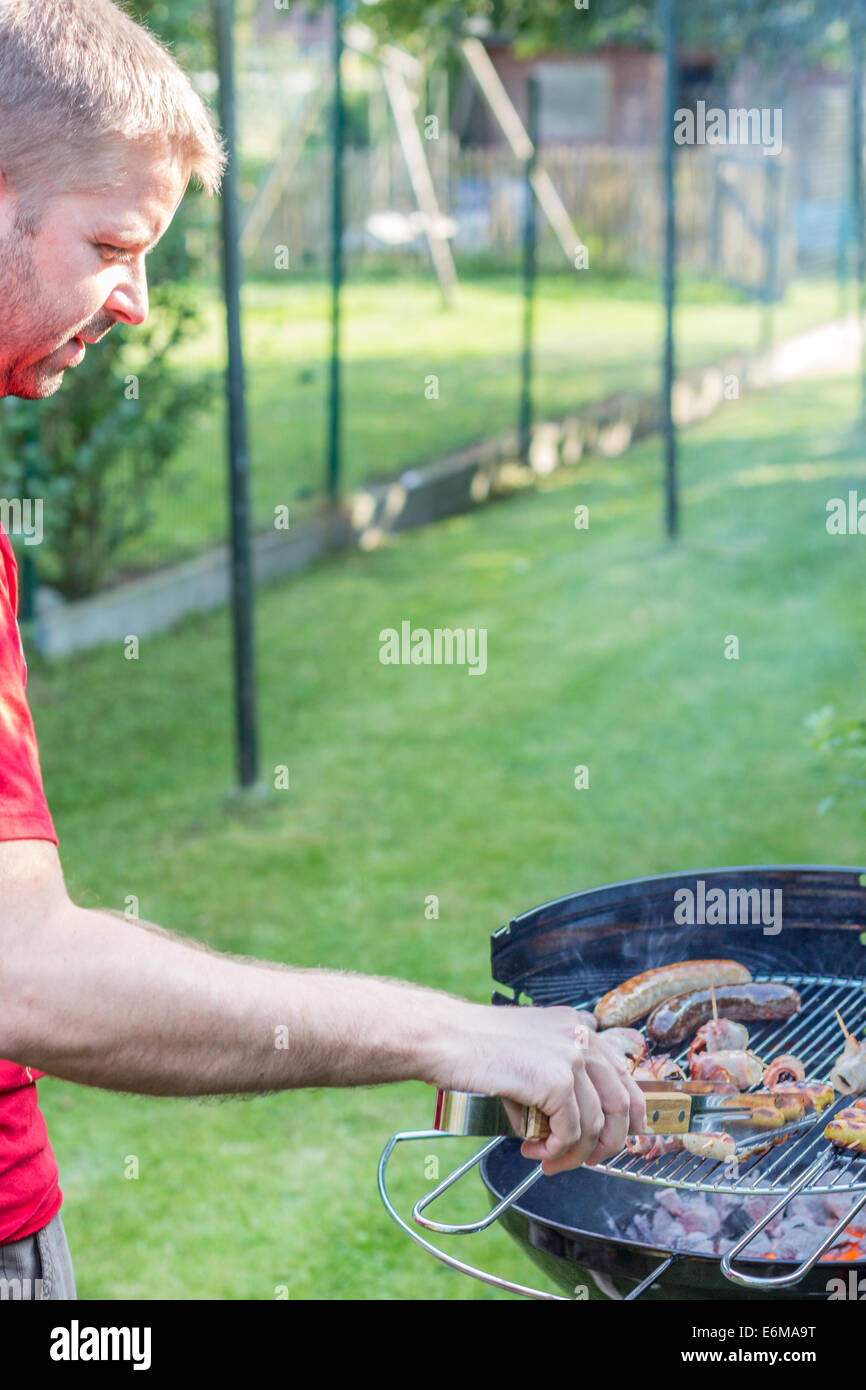 Man cooking meat on the barbecue - left-side Stock Photo - Alamy
