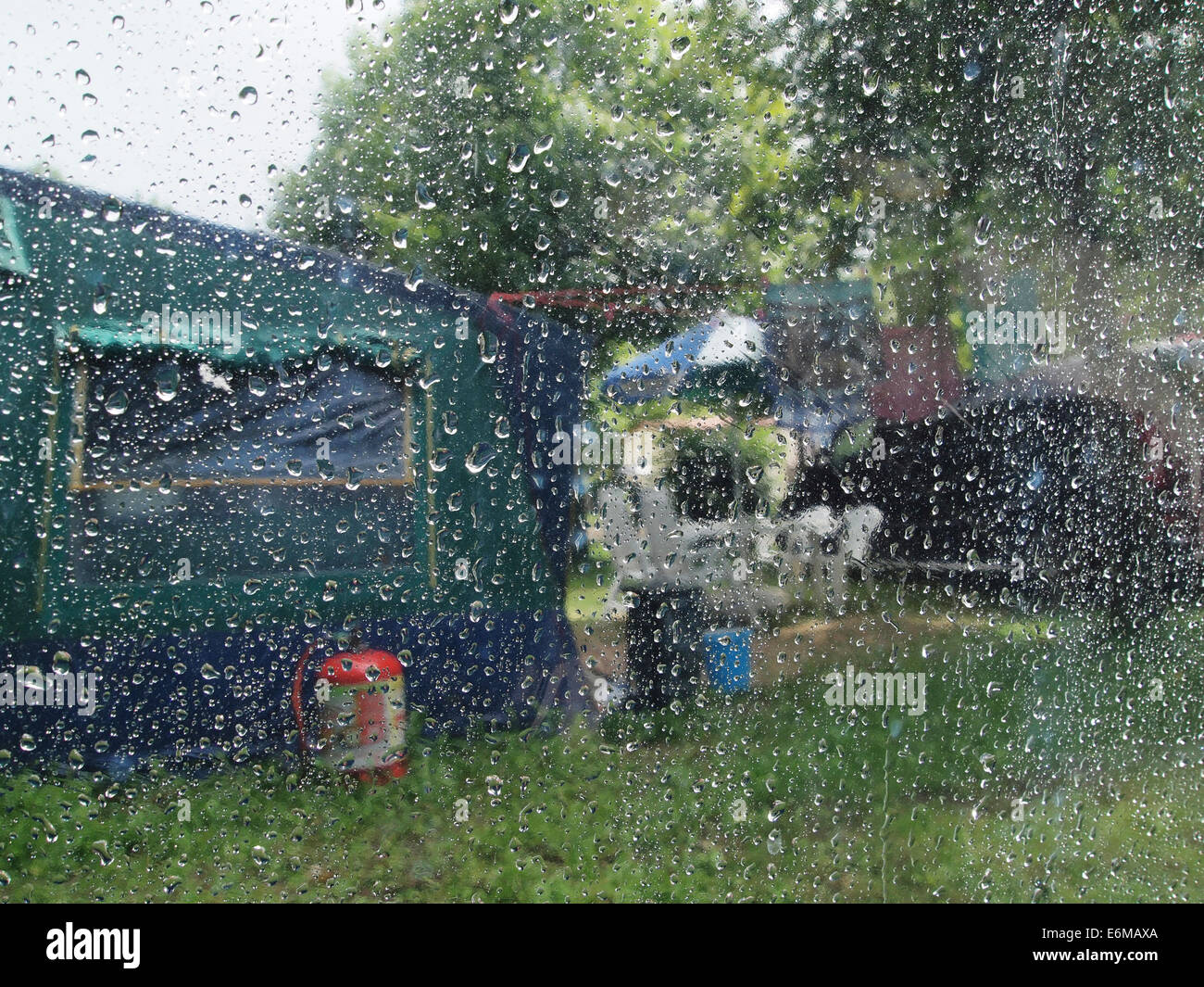 Waterdrops on a tent window, looking out, with blurred camping site visible. Domaine de Chalain, Jura, France Stock Photo