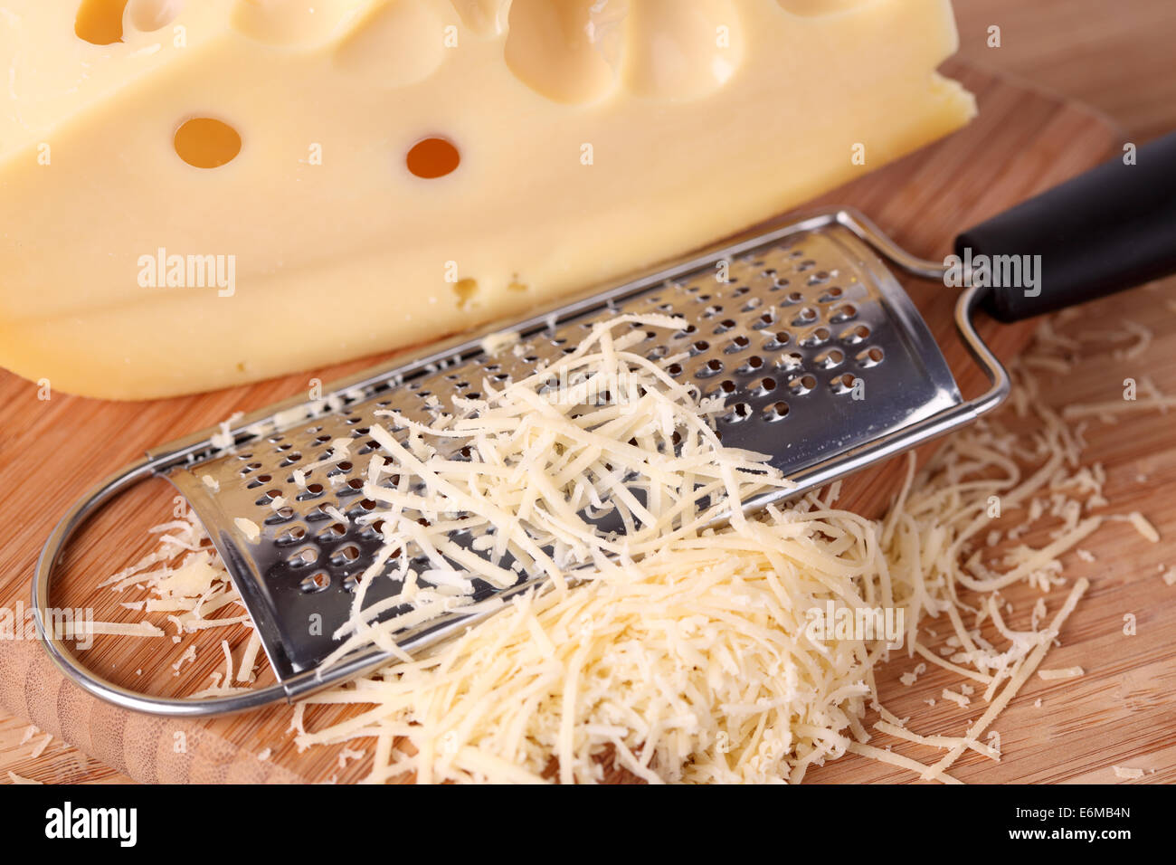 Grated cheese and grater on a wooden cutting board Stock Photo