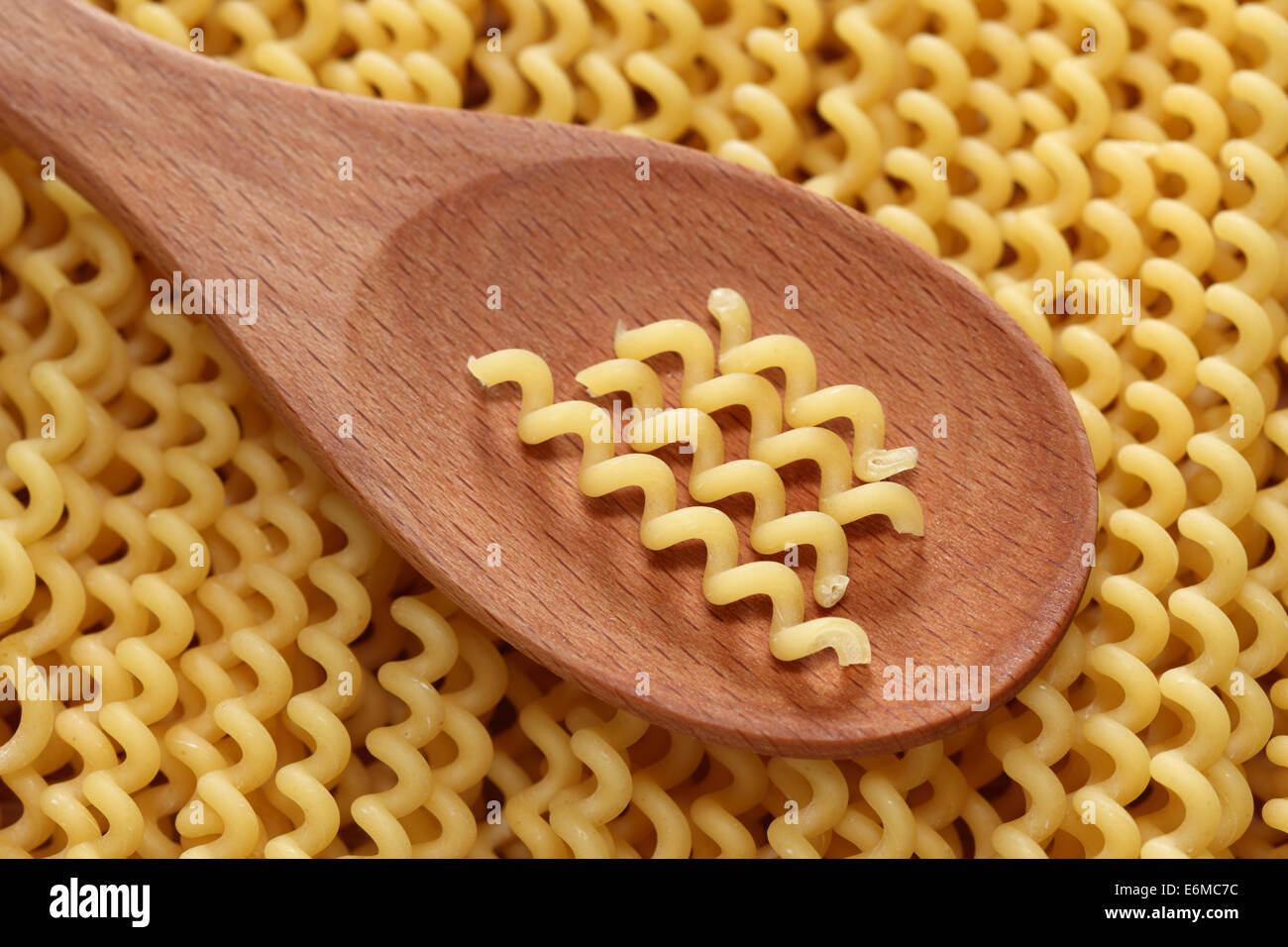 Pasta fusilli (Fusilli lunghi bucati) in a wooden spoon on pasta fusilli background Stock Photo