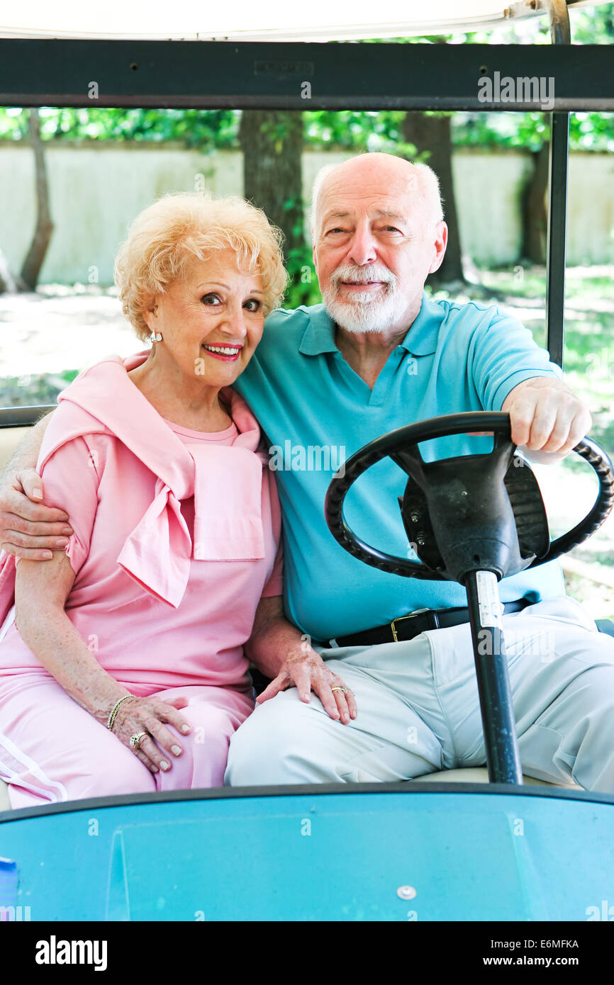 Senior couple uses a golf cart for transportation in their adult community. Stock Photo