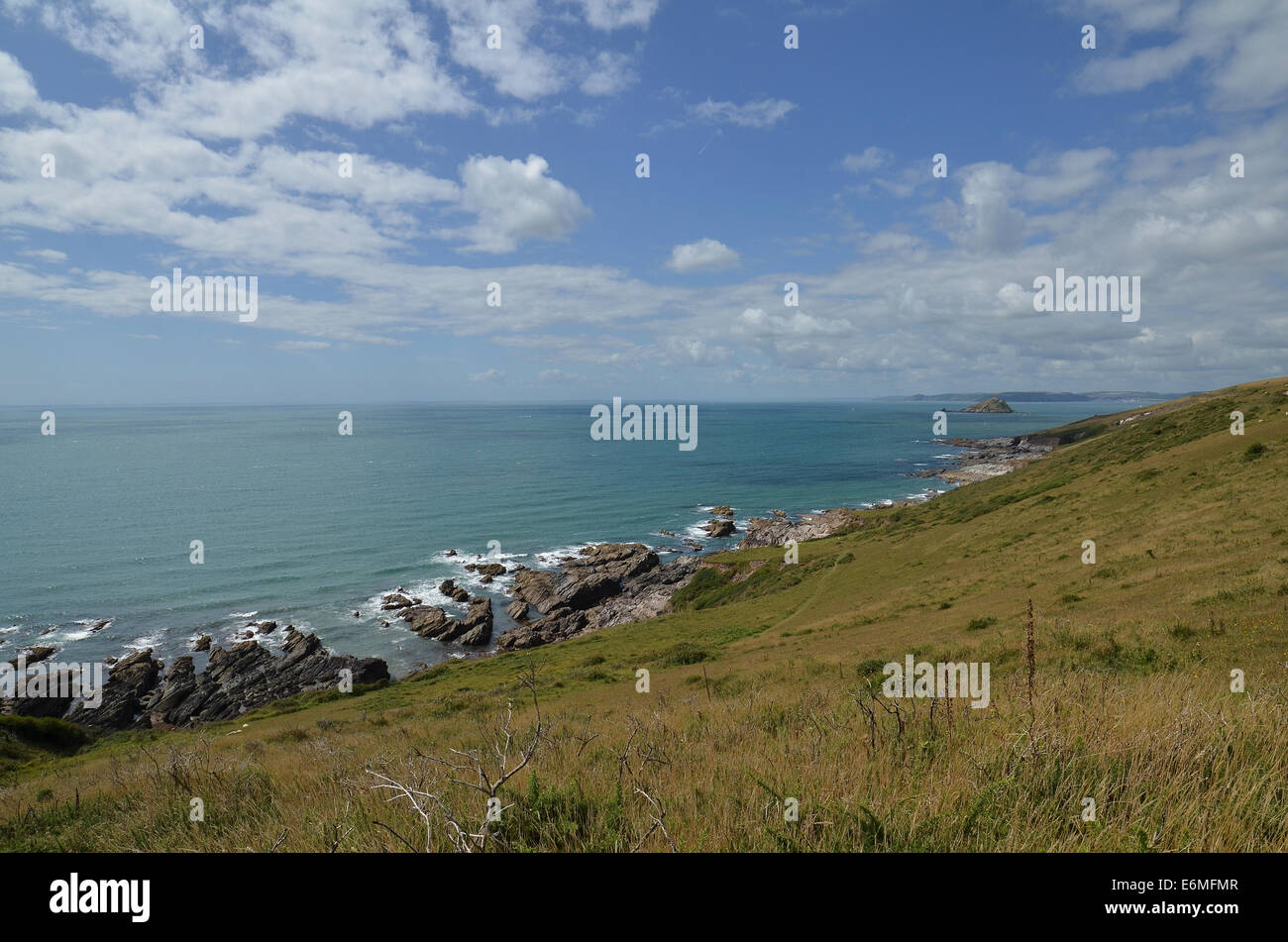 Looking out to sea with the Mewstone in the distance  from the rocky cliffs in Noss Mayo, Devon. Stock Photo