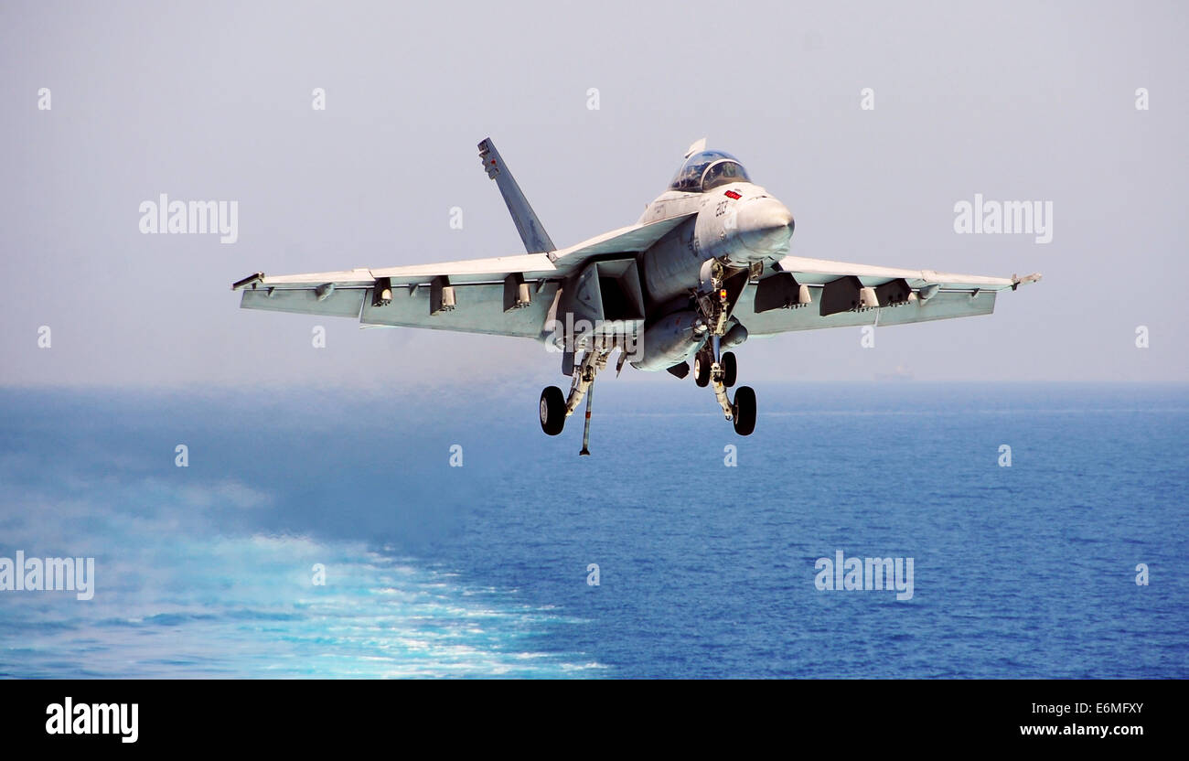 A US Navy F/A-18F Super Hornet fighter aircraft prepares to land on the flight deck of the aircraft carrier USS George H.W. Bush August 22, 2014 in the Arabian Gulf. The pilots are flying targeted airstrikes against extremists known as the Islamic State in Iraq and the Levant. Stock Photo
