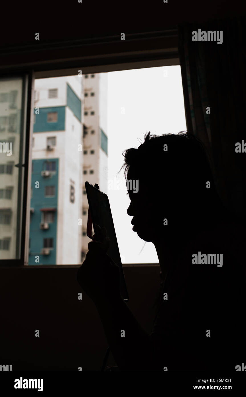 a silhouette of a female doing make up facing the mirror Stock Photo