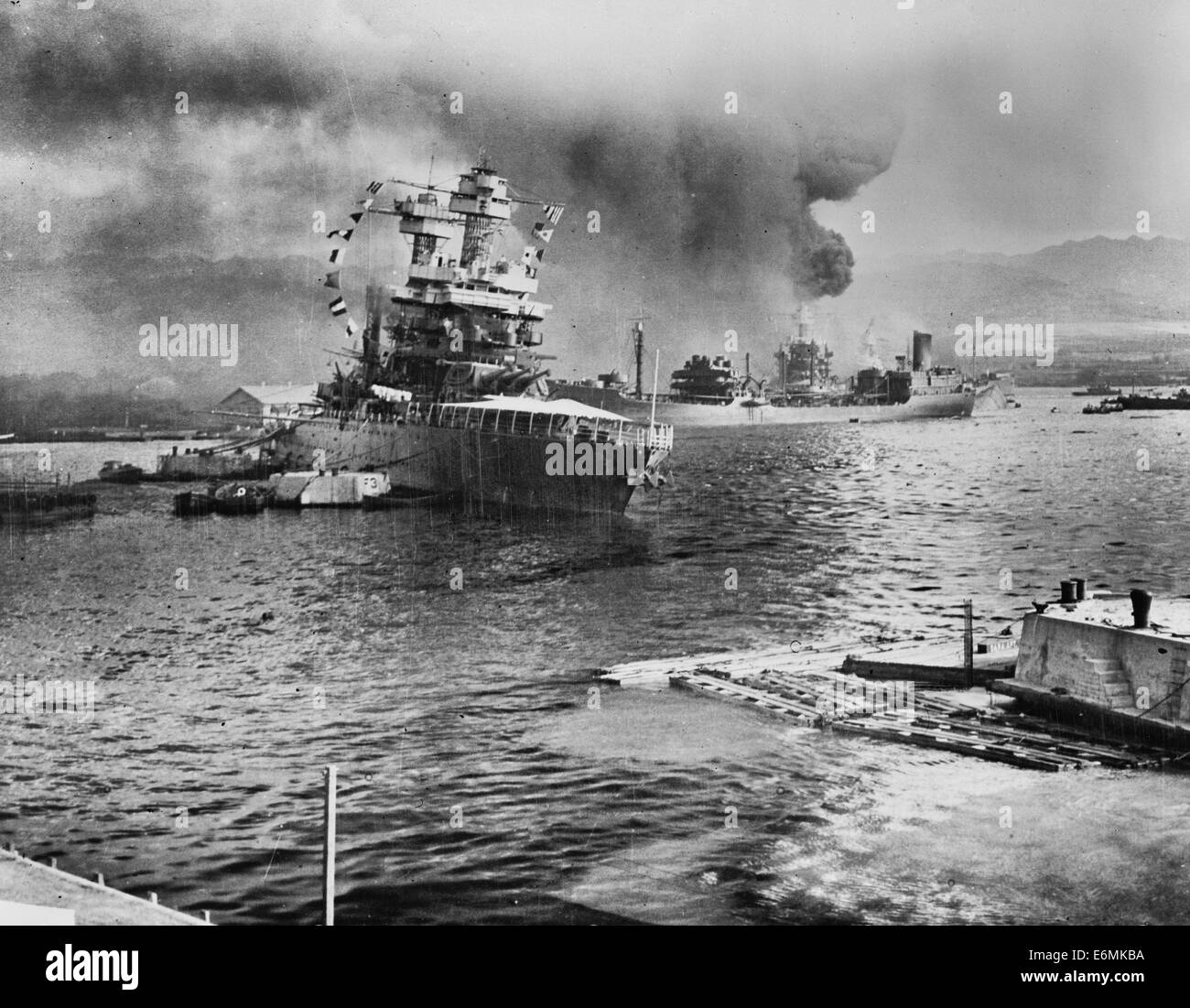 Leaves berth virtually surrounded by stricken ships. The U.S.S. Neosho, navy oil tanker, cautiously backs away from her berth (right center) in a successful effort to escape the Japanese attack on Pearl Harbor, Dec. 7, 1941. At left the battleship U.S.S. California lists after aerial blows. Other crippled warships and part of the hull of the capsized U.S.S. Oklahoma may be seen in the background. The Neosho was later sunk in the Coral Sea Stock Photo