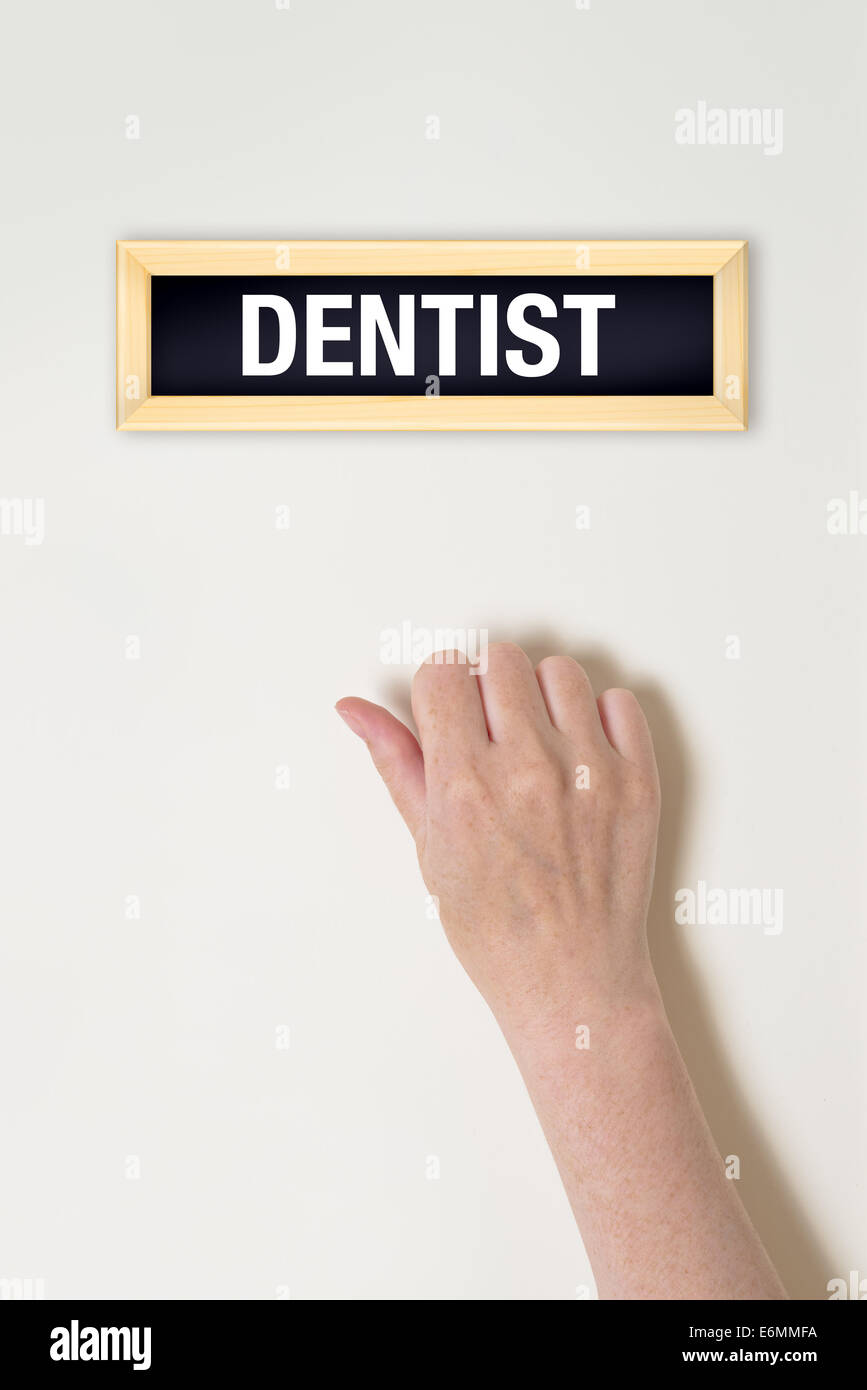 Female hand is knocking on Dentist door for a medical exam Stock Photo