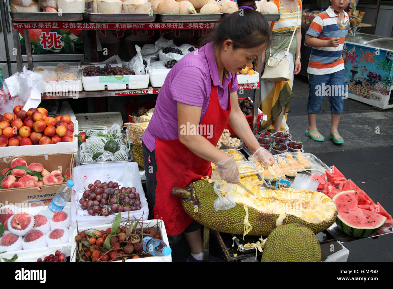 Beijing, China. 04th July, 2014. A woman cuts a durian (cheese fruit) on a market in Beijing, China, 04 July 2014. Photo: Friso Gentsch/dpa/Alamy Live News Stock Photo