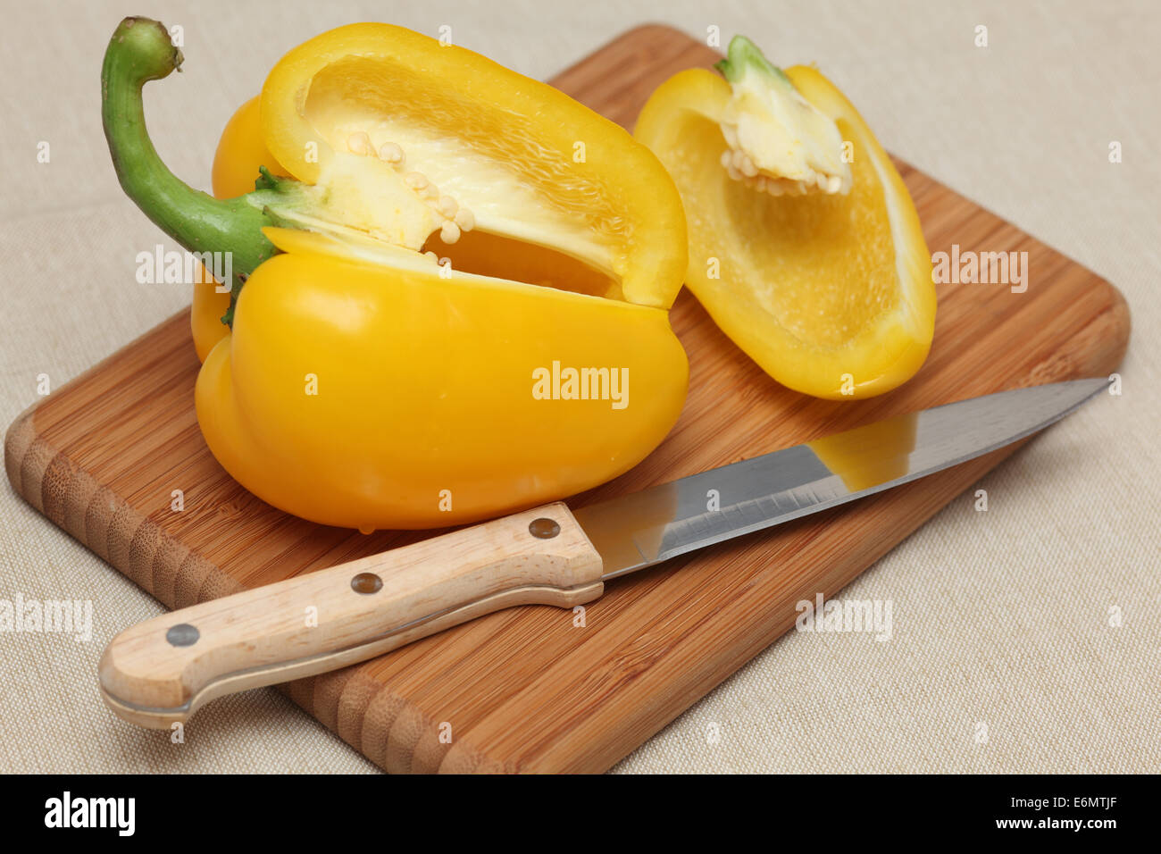 Yellow bell pepper on a cutting board with knife. Closeup. Stock Photo