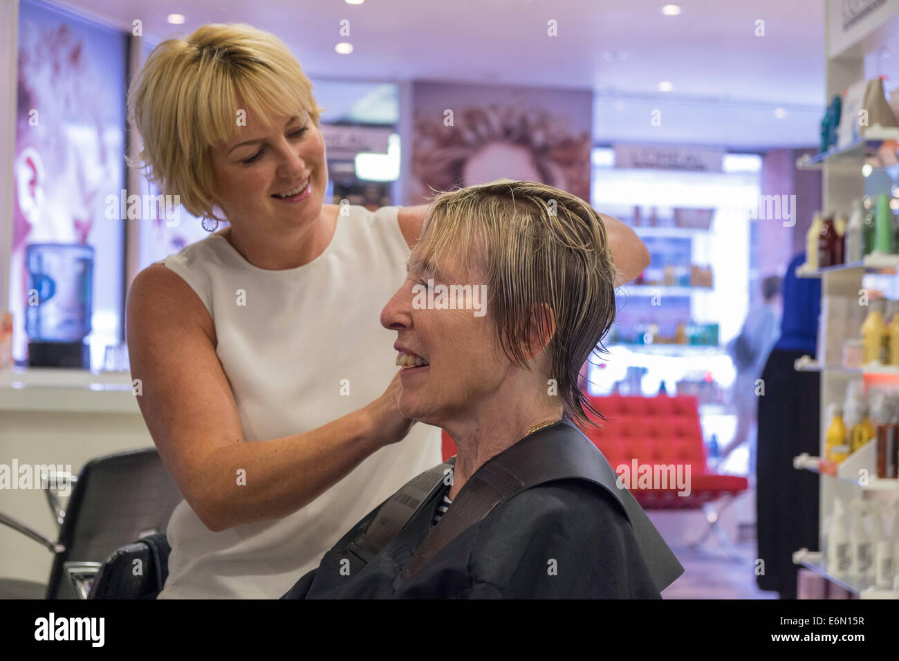 OLDER WOMAN IN HAIR SALON HAVING HAIR CUT AND STYLED BY HAIRDRESSER