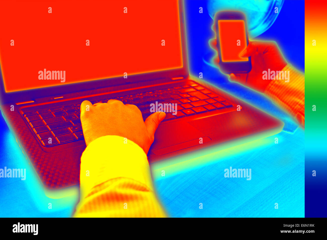 Infrared thermography image showing the heat and radiation of Notebook and smartphones in the office Stock Photo