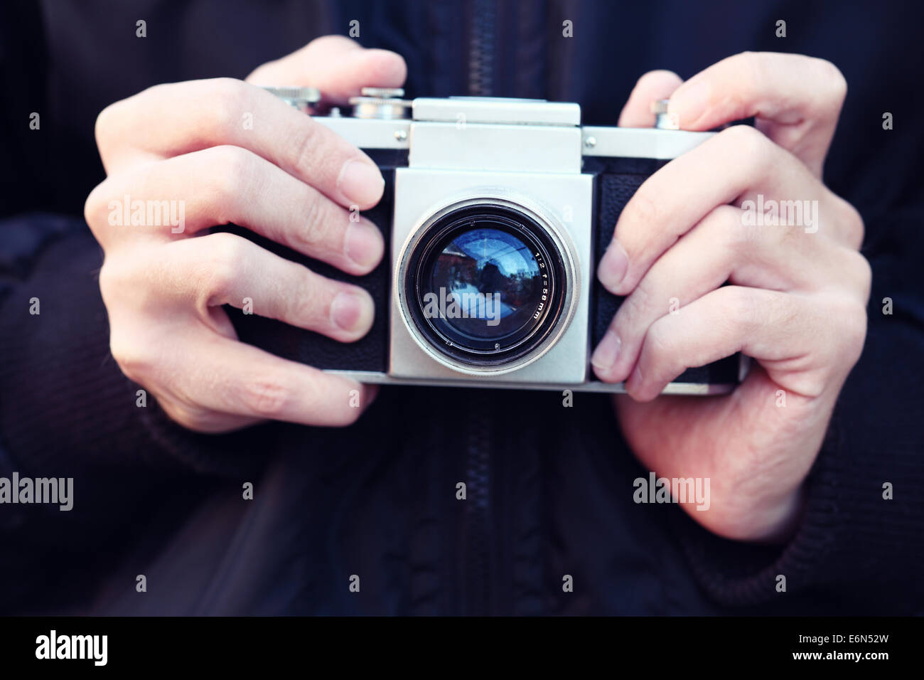 Old film camera in the hands of the photographer. Close-up. Cross ...