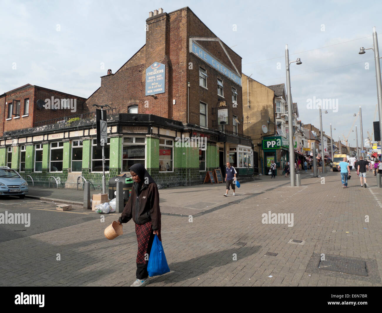 Woman people walking by The Chequers pub in Walthamstow High Street