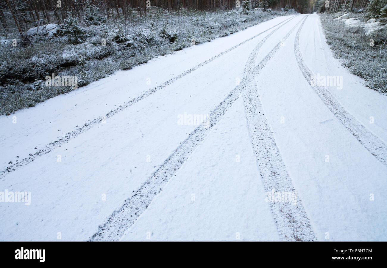 Car tracks on snowy empty forest road , Finland Stock Photo