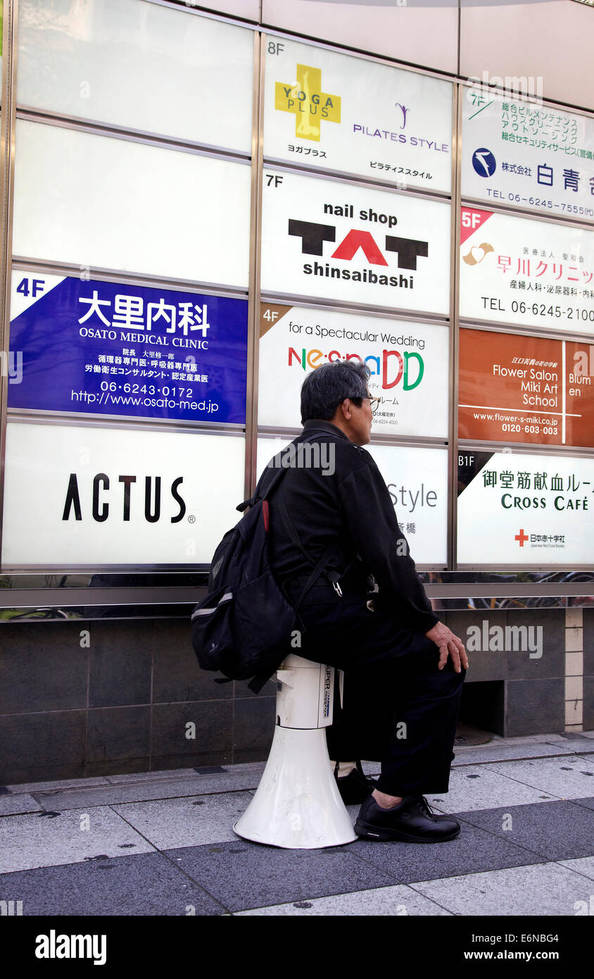 Elderly japanese man sitting, relaxing, resting on megaphone. Tokyo, Japan, Asia Stock Photo