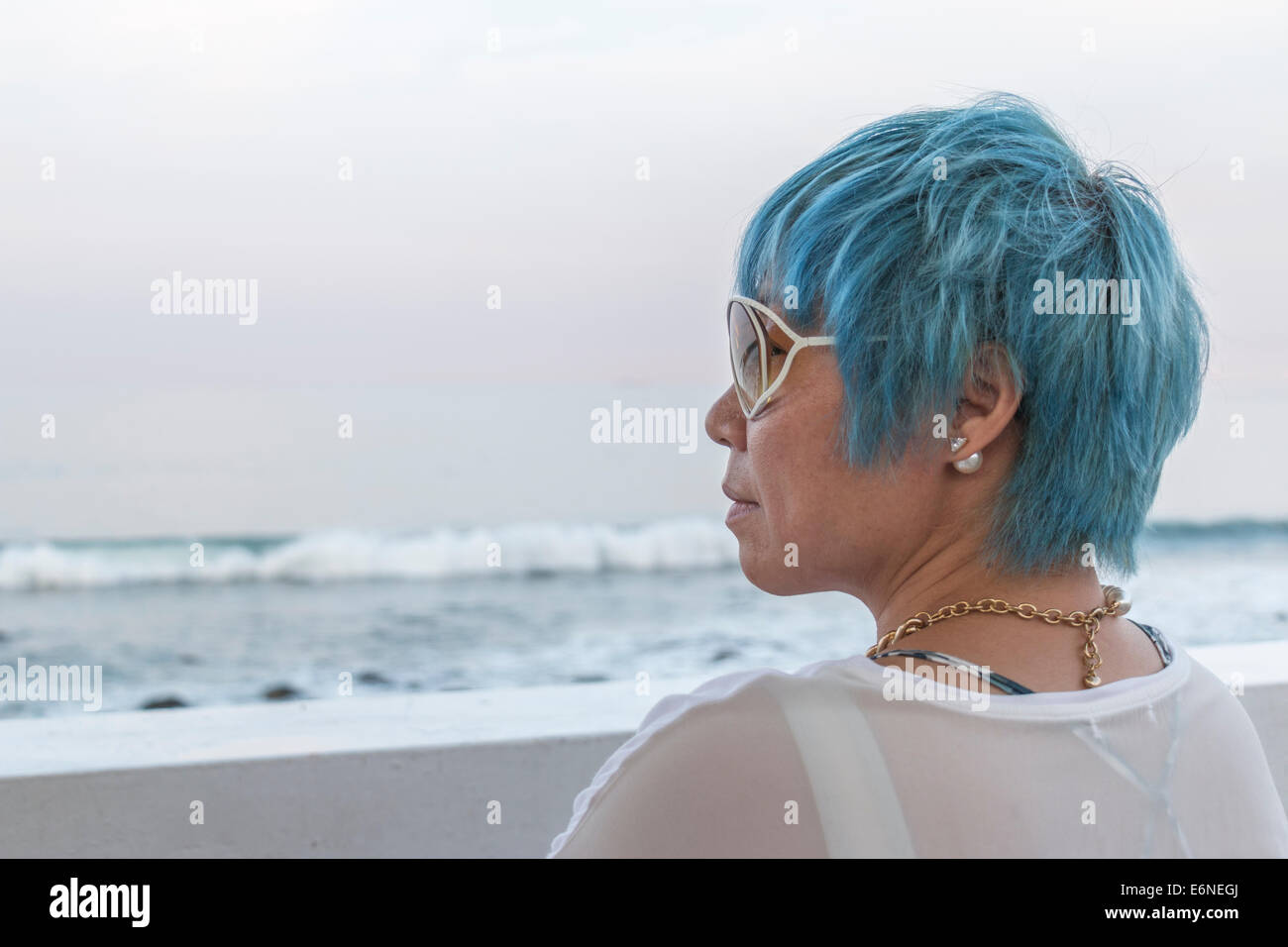 Contemplative woman sitting by the Pacific Ocean coast in northern Taiwan Stock Photo