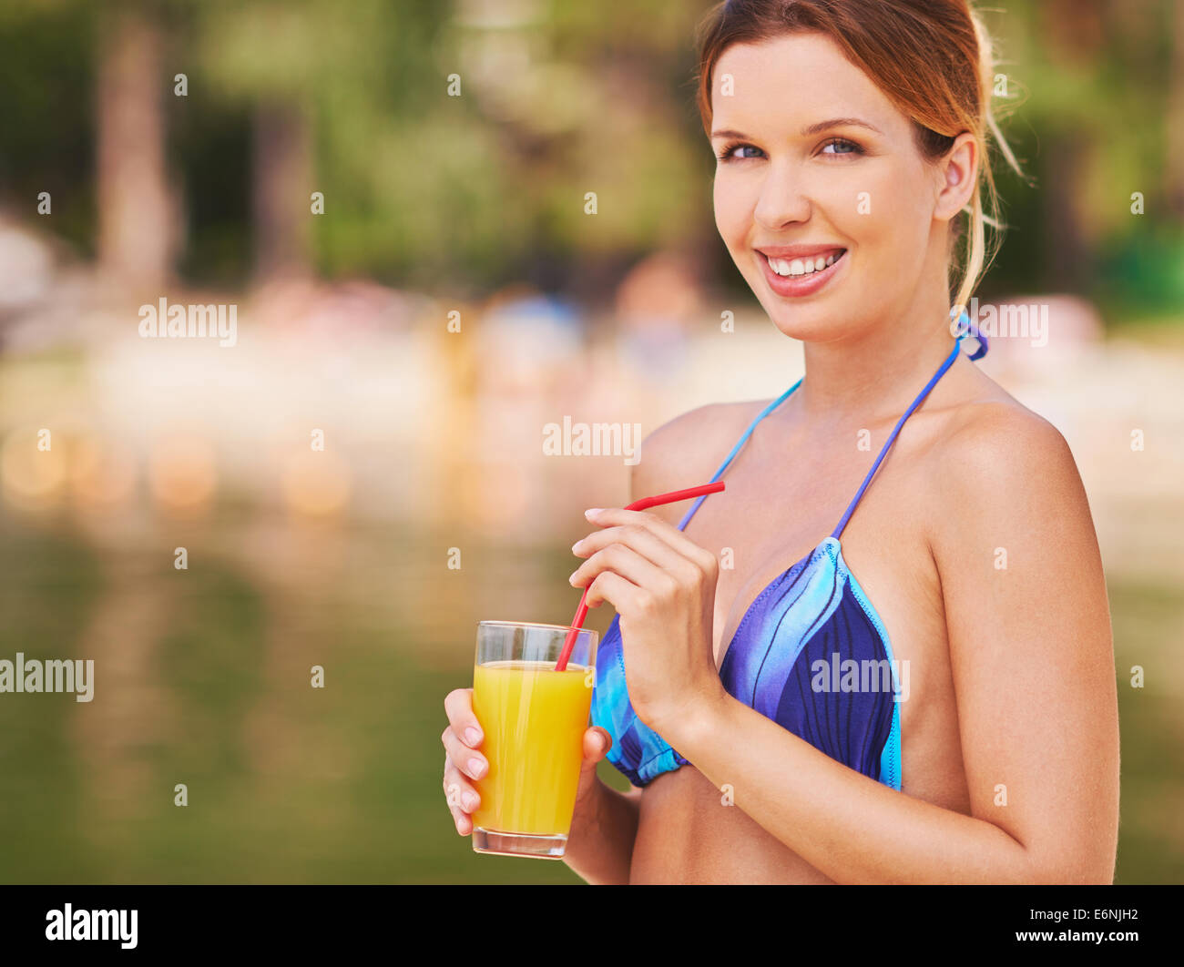 Young woman in bikini with juice looking at camera and smiling Stock Photo