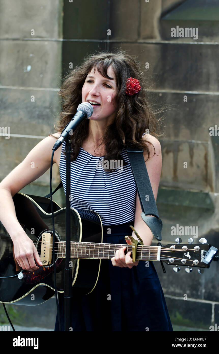 Attractive female singer/guitarist busking at the annual Festival Fringe in Edinburgh, Scotland. Stock Photo