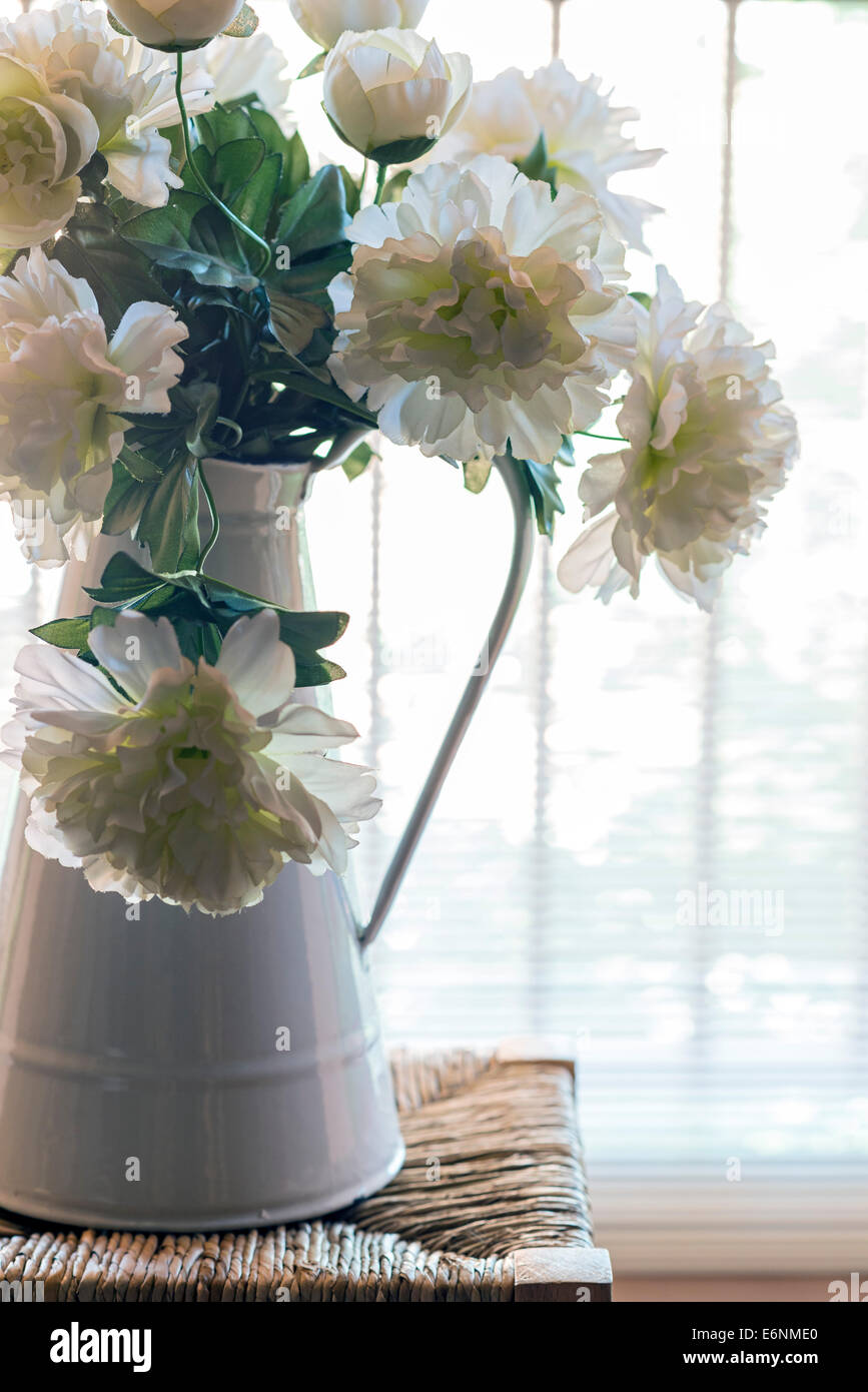 artificial flowers in an enamel jug. backlight Stock Photo