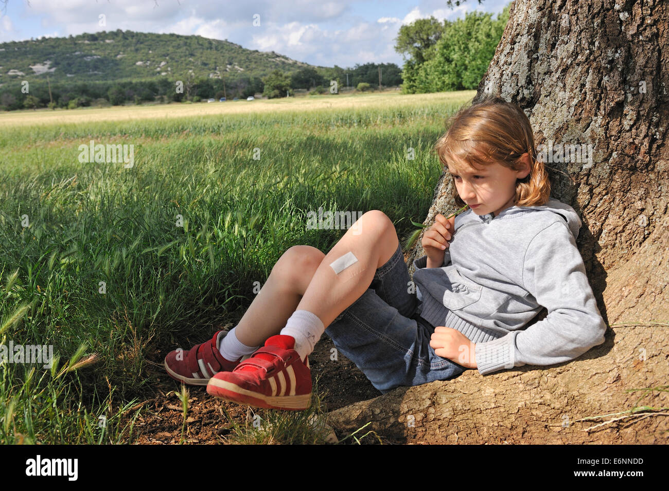 Little girl (aged 9) thinking sitting under a tree Stock Photo