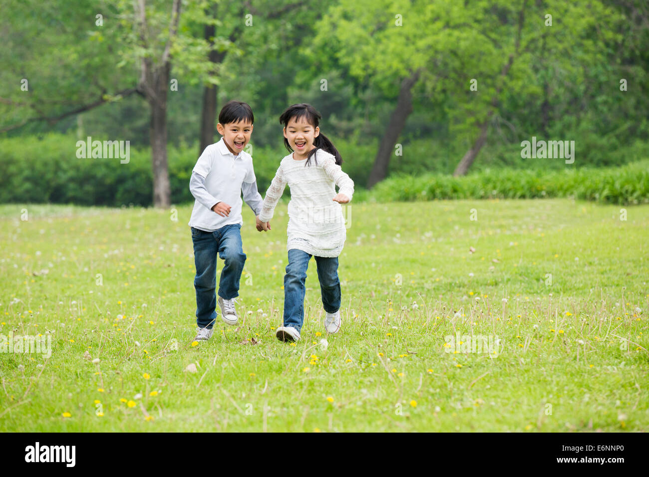 Happy children holding hands running on the grass Stock Photo - Alamy