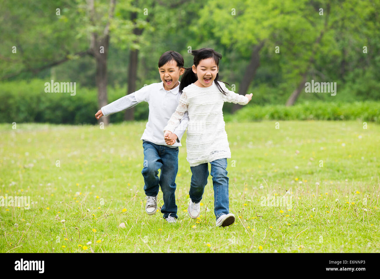 Happy children holding hands running on the grass Stock Photo - Alamy