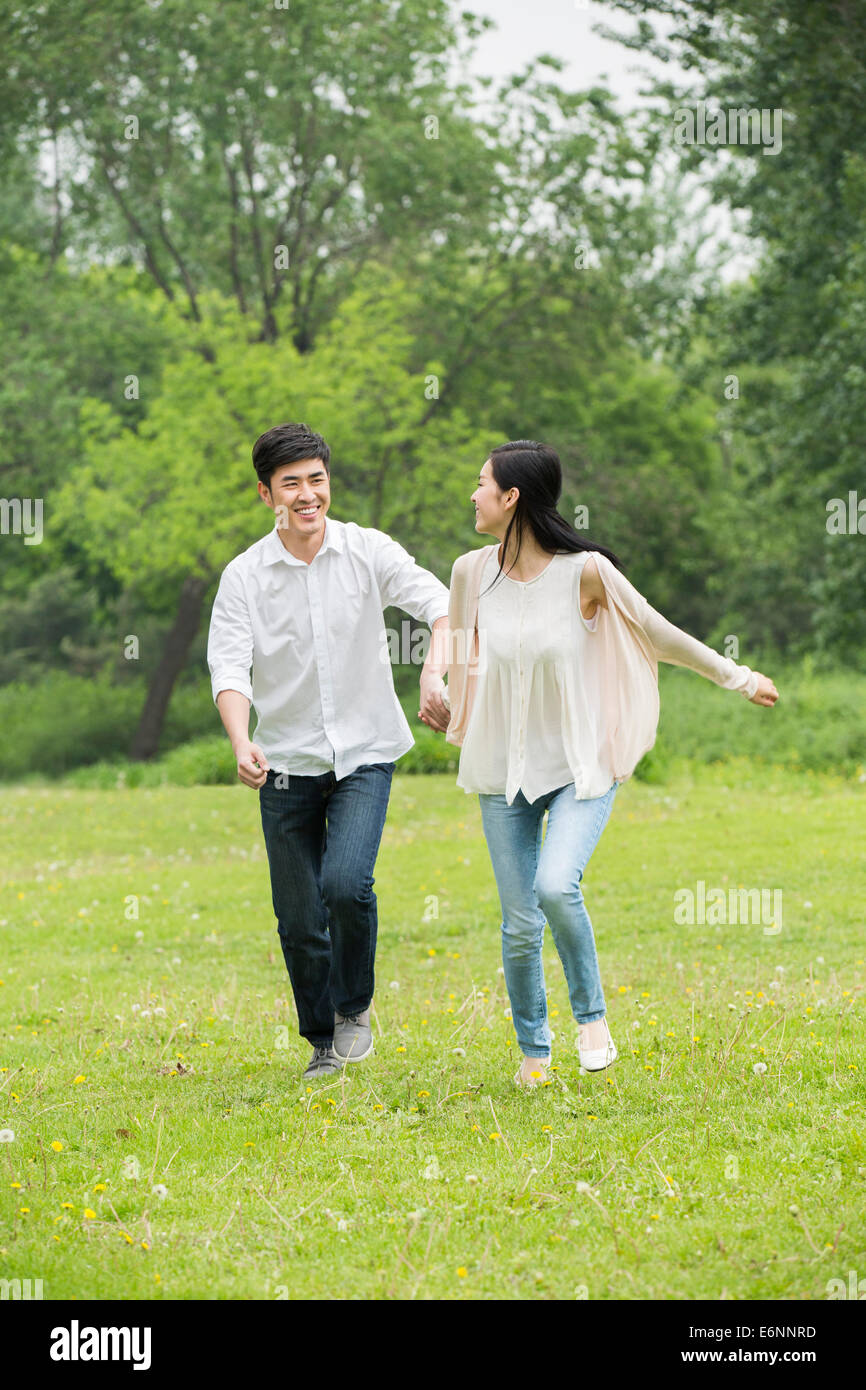 Happy young couple holding hands running Stock Photo - Alamy