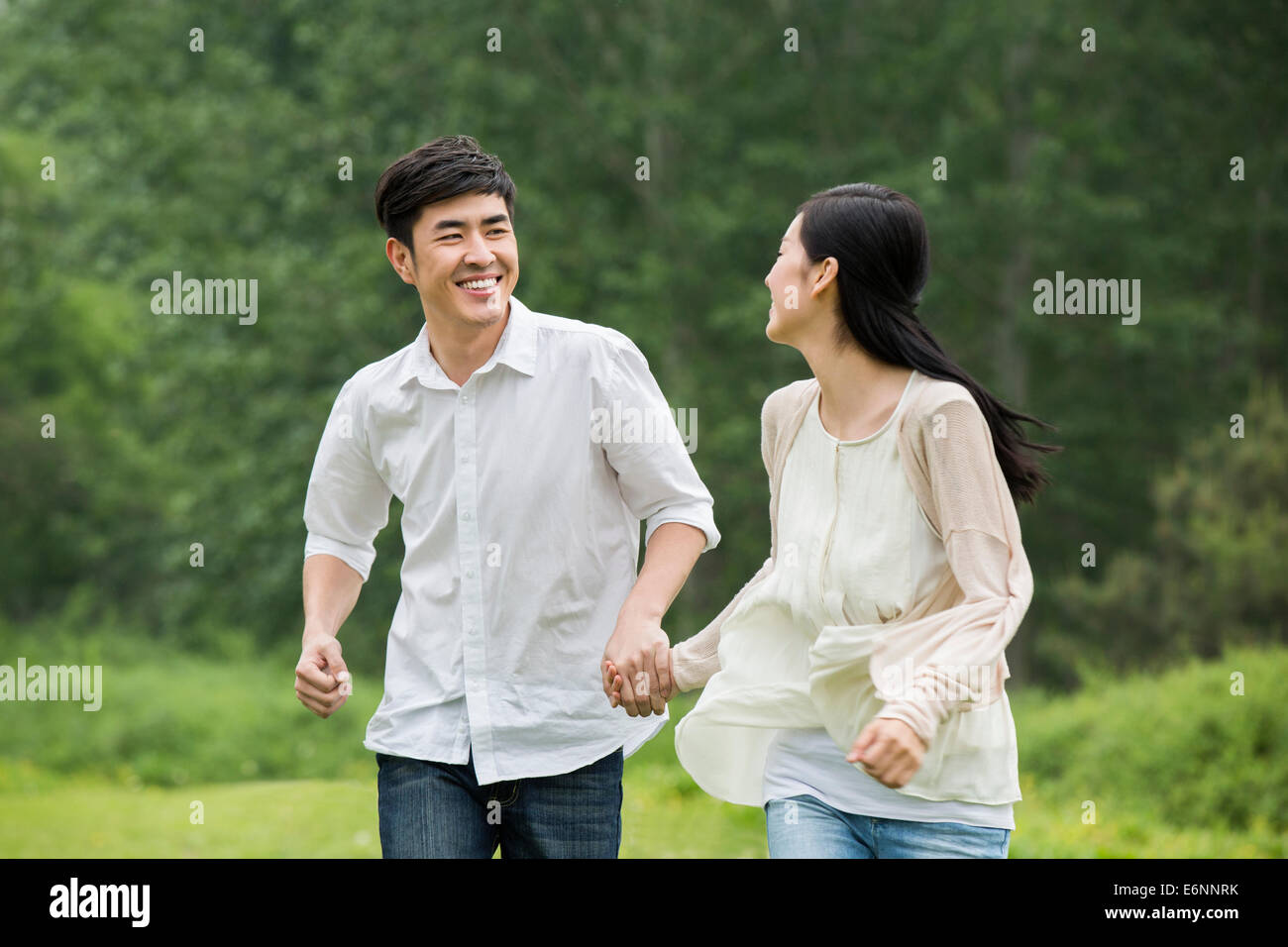 Happy young couple holding hands running Stock Photo - Alamy