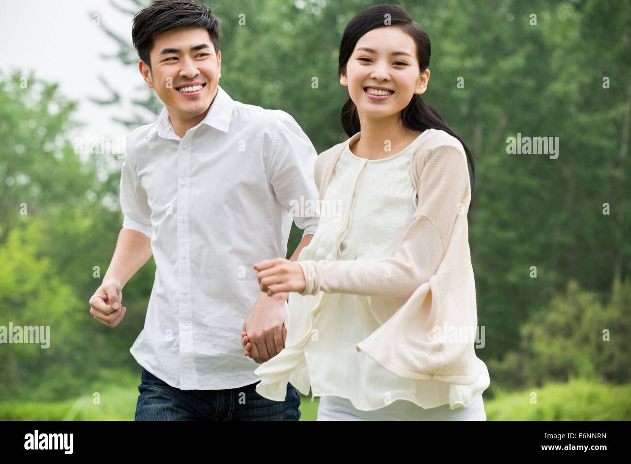 Happy young couple holding hands running Stock Photo - Alamy
