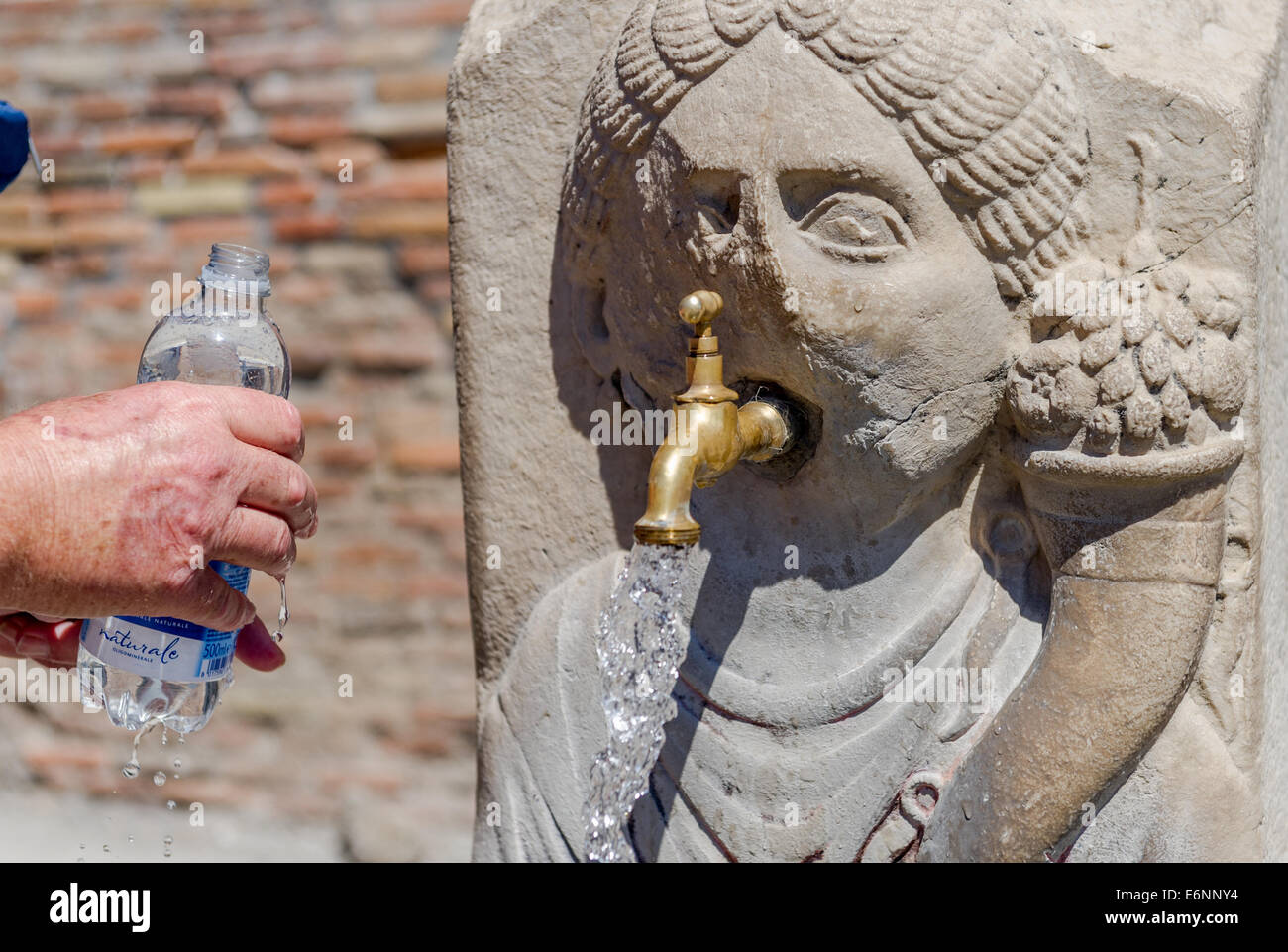 Female stone carving head used as a water drinking outlet for a brass tap. Stock Photo