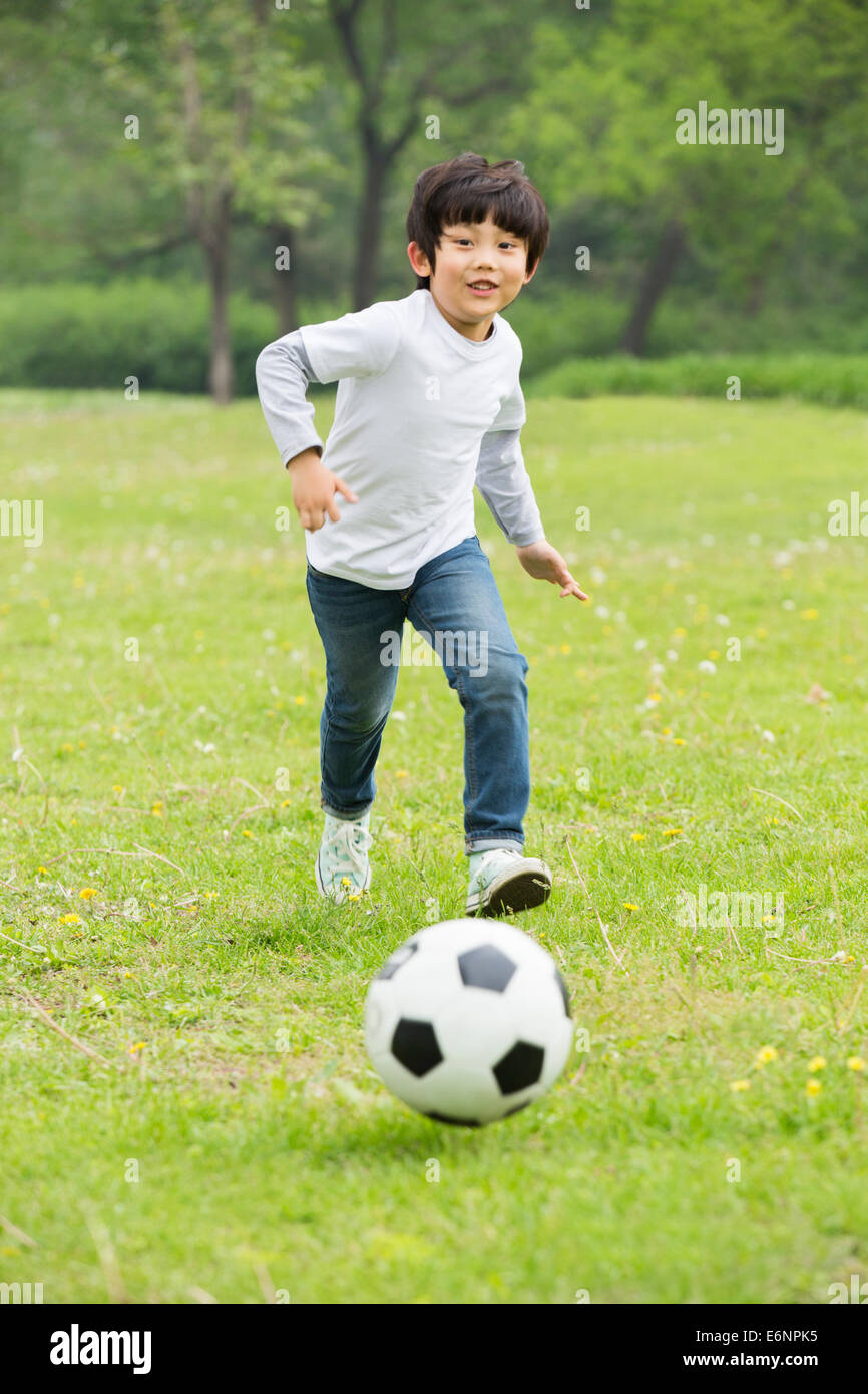 Happy boy playing football on the grass Stock Photo