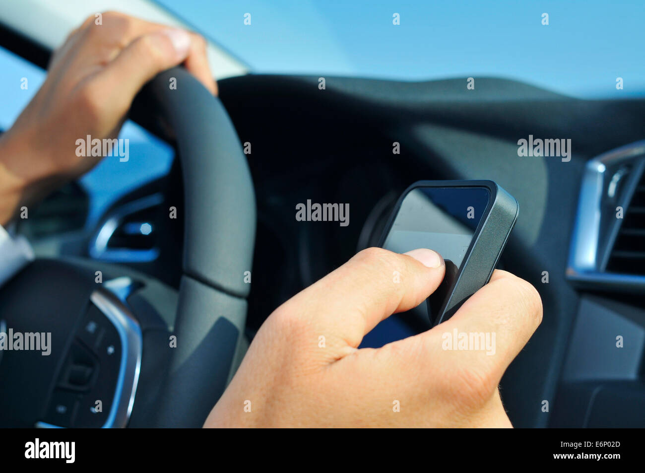 closeup of a man using a smartphone while driving a car Stock Photo