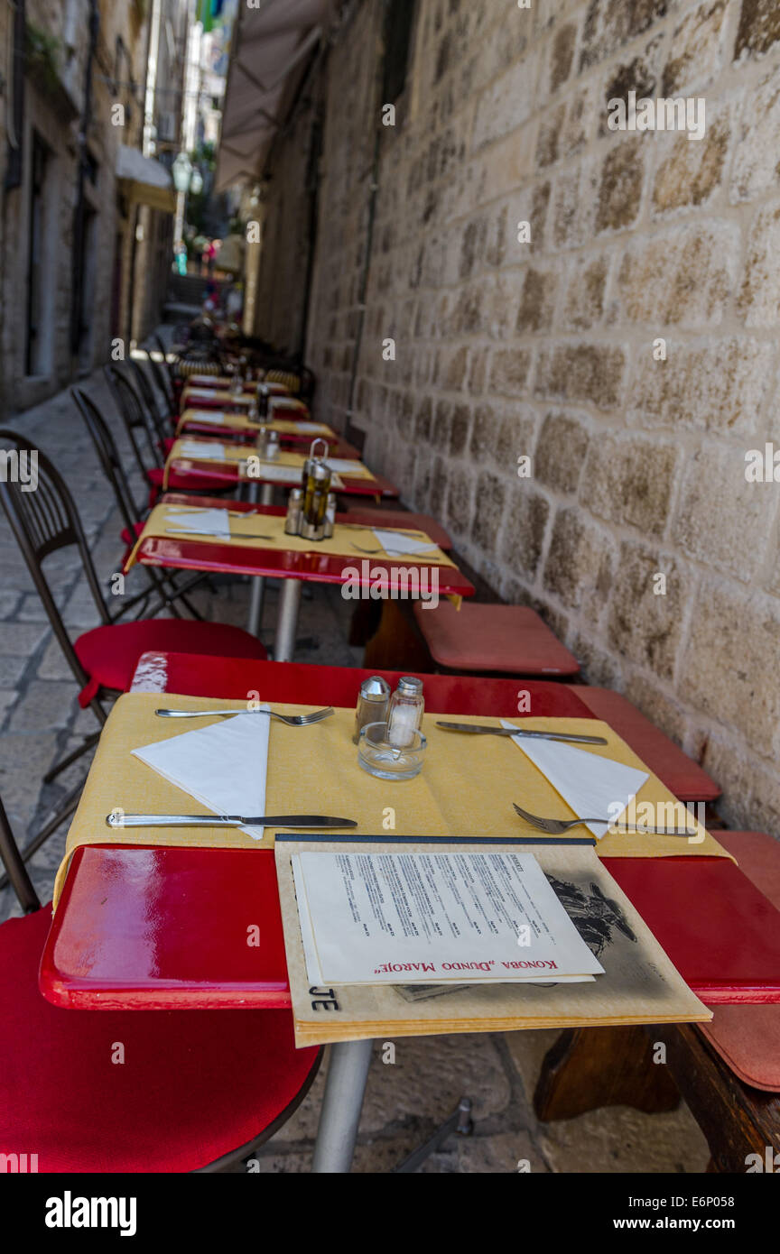 Row of empty restaurant tables with menus in a back street of Dubrovnik in Croatia. Stock Photo
