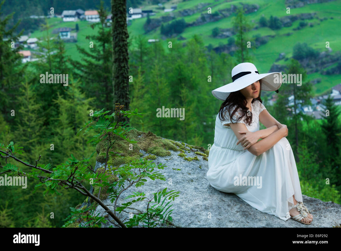 Woman in white dress and white hat staying on a big stone in the ...