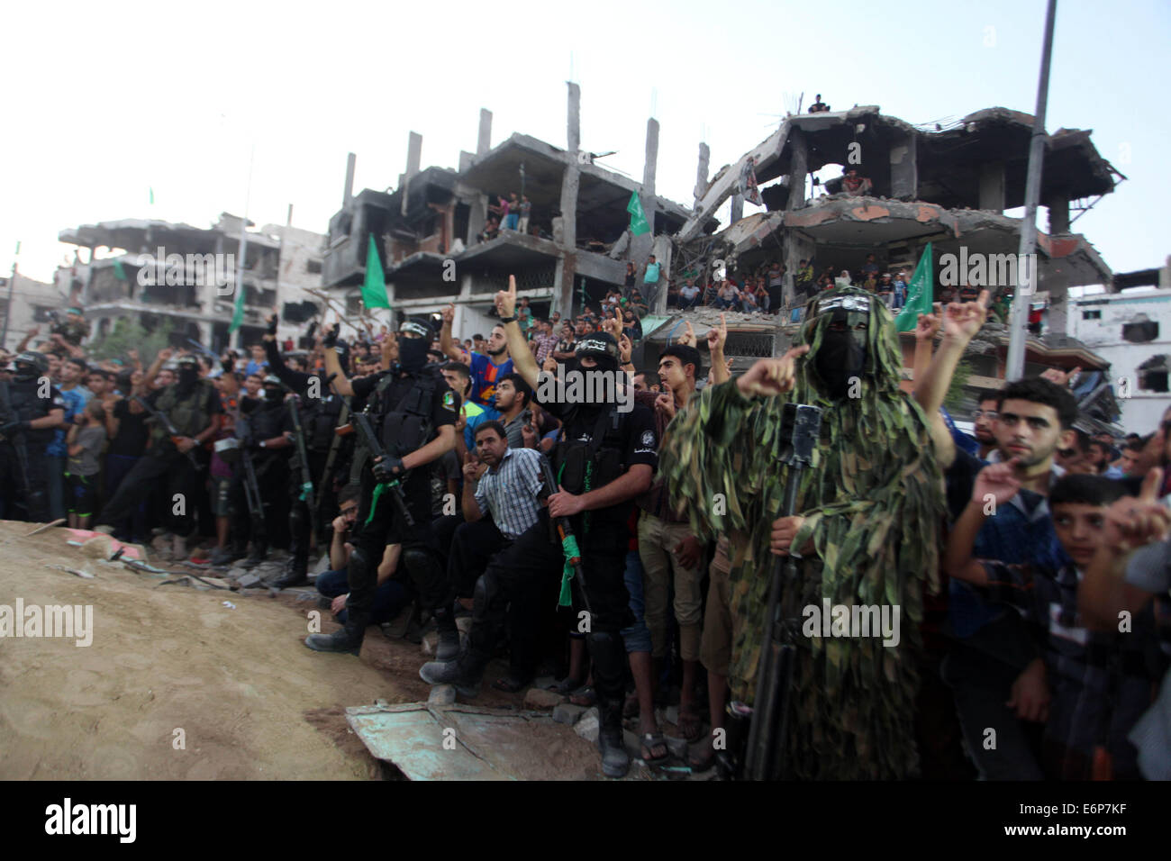 Gaza City, Gaza Strip, Palestinian Territory. 27th Aug, 2014. Palestinian militants of Izzedine al-Qassam Brigades, military wing of Hamas, and their supporters celebrate a victory rally at the debris of destroyed houses in Shijaiyah, neighborhood of Gaza City, in the northern Gaza Strip, Wednesday, Aug. 27, 2014. An open-ended cease-fire between Israel and Palestinian militants in the Gaza Strip was holding Wednesday Credit:  Ashraf Amra/APA Images/ZUMA Wire/Alamy Live News Stock Photo