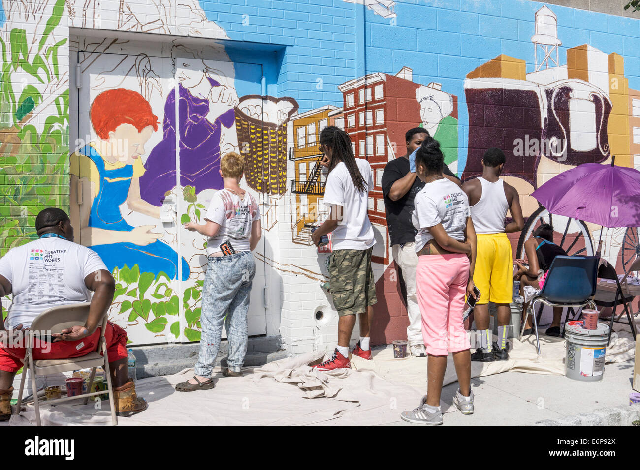 colorful multiracial young New Yorkers & former PAL kids in group effort to paint mural celebrating 100th anniversary PAL Stock Photo