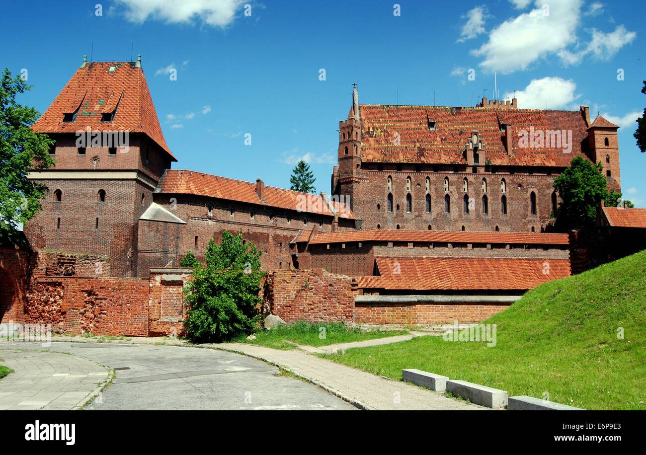 Malbork, Poland:  Brick outer defense walls, massive Knight's Hall, and watch towers at 14th-15th century Malbork Castle Stock Photo