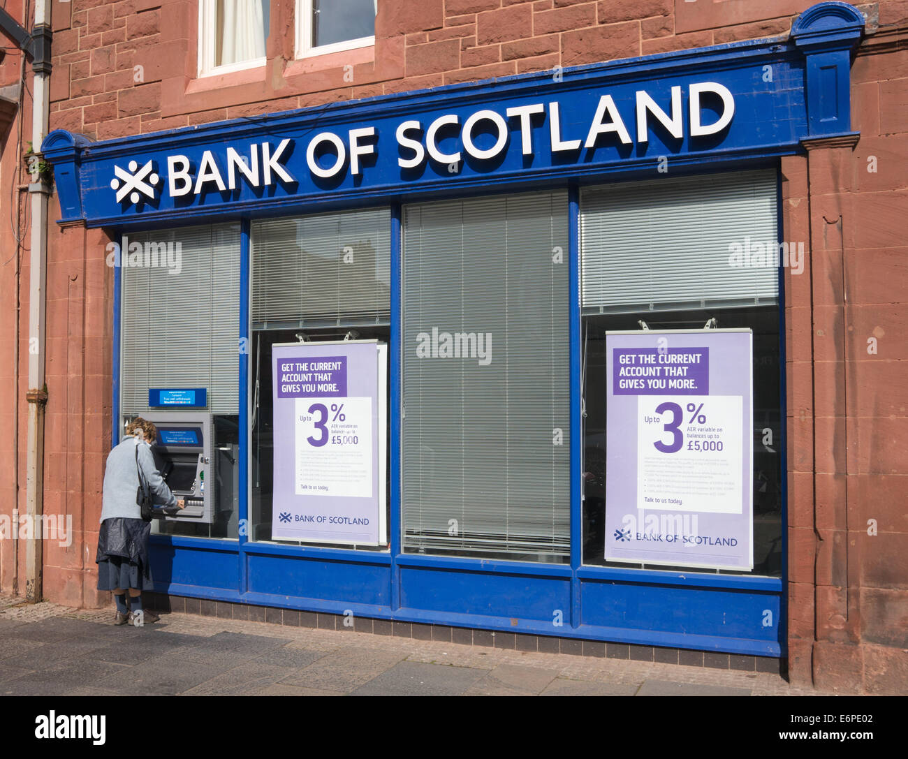 Woman withdrawing money from ATM at  Bank of Scotland, Dunbar, East Lothian, Scotland, Europe Stock Photo