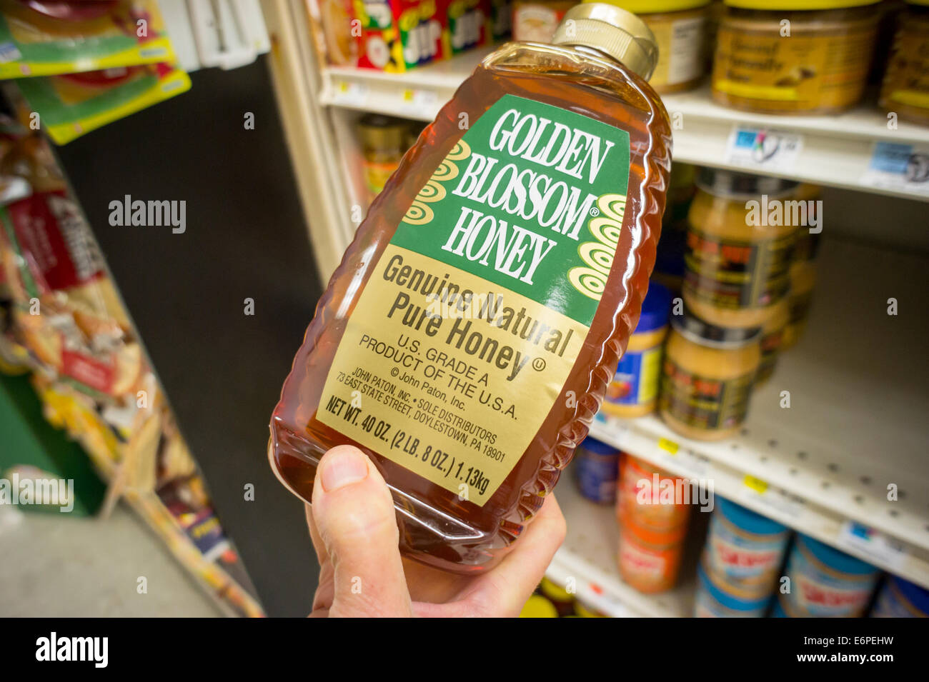 A shopper chooses a bottle of Golden Blossom Honey blend, a "product of