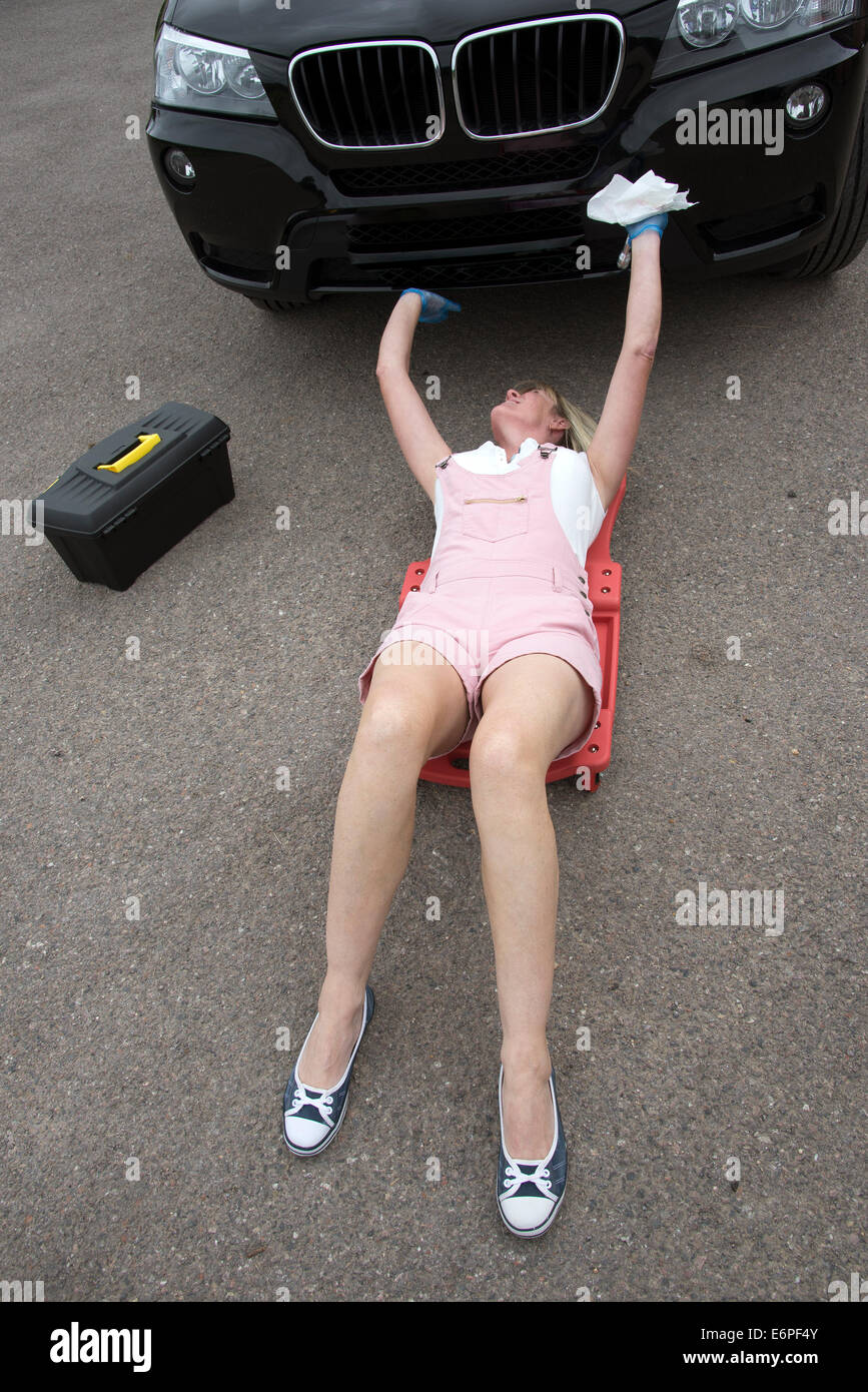 Working on a car female motor mechanic laying on a crawler to gain access under a car Stock Photo