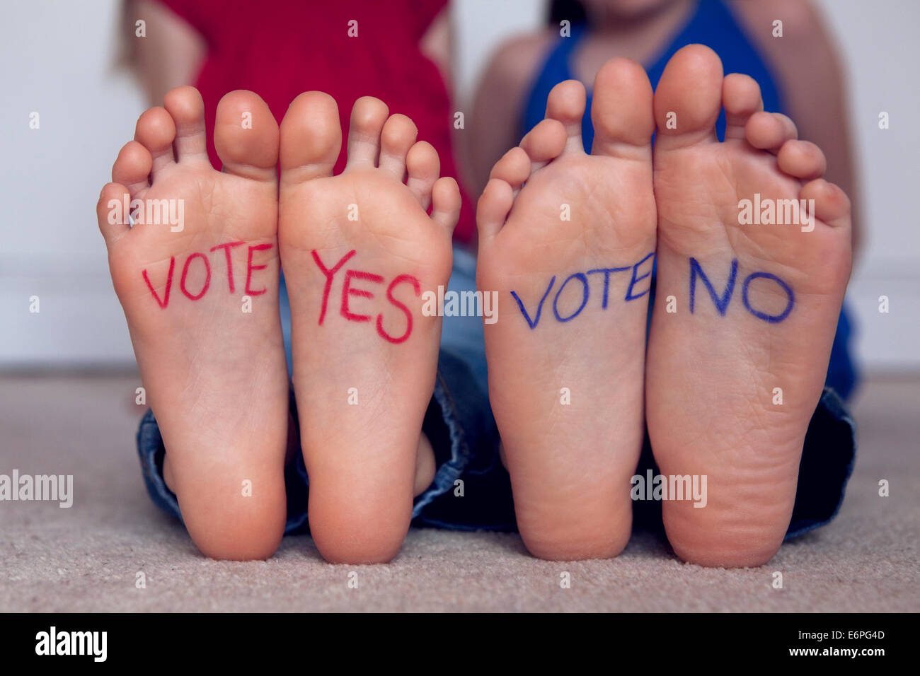 Red 'vote yes' and blue 'vote no', written on children's feet. Conceptual 'to vote with your feet'. Stock Photo