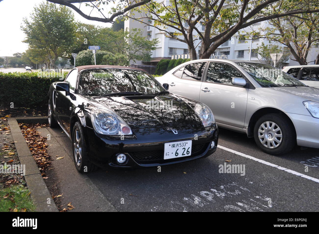 Photograph of a Japanese roadster sports car, taken outside, next to a common economy car Stock Photo