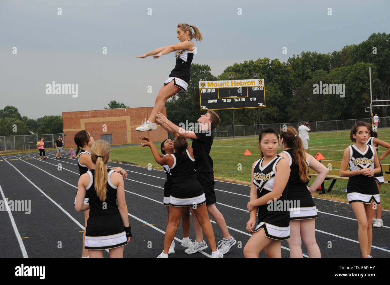 high school cheerleaders perform at a high school football game Stock Photo