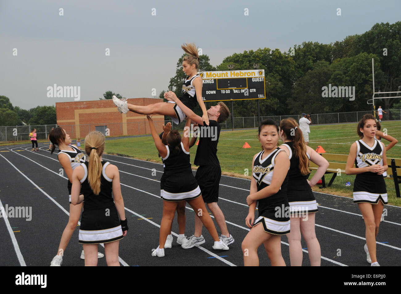 high school cheerleaders perform at a high school football game Stock Photo