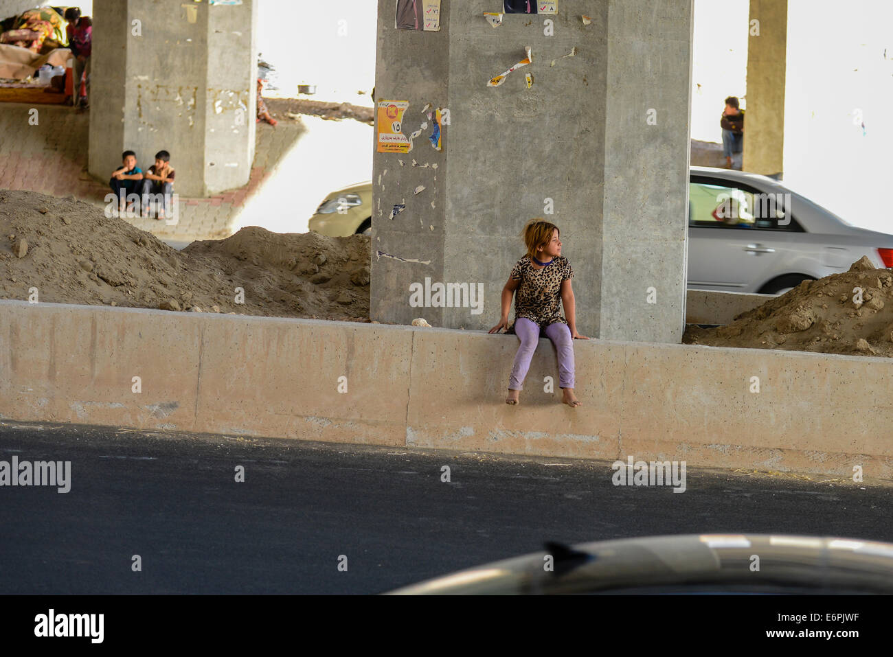 A young girl sits amonst the traffic. These Yezidi Refugees are living by the side of the road